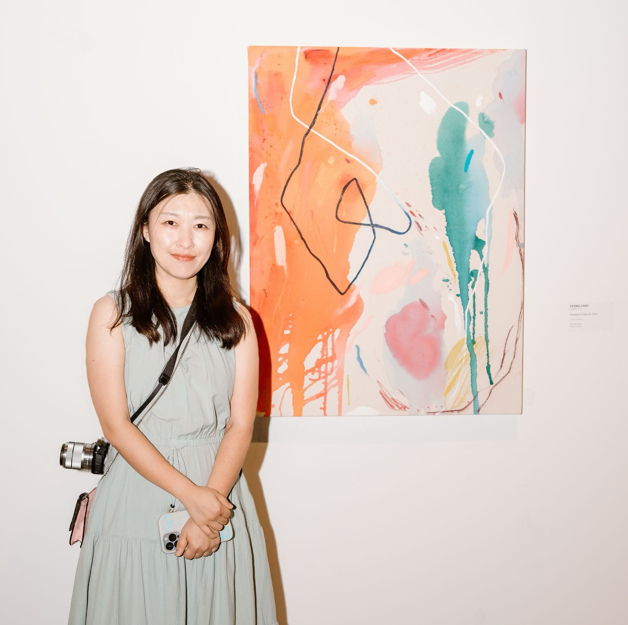 Zifeng Zang standing beside her abstract painting.